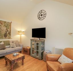 A living room with a sofa and television at The Little Loft in Burford