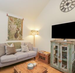 A living room with a sofa and television at The Little Loft in Burford