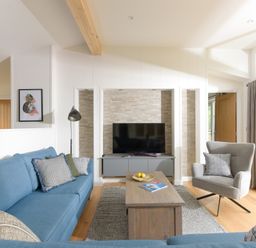 A living room with a blue sofa a wooden coffee table and a gray armchair at 5 Southern Place in Dobwalls