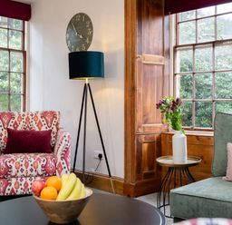 A sitting area with patterned armchair green sofa fruit bowl and flowers at Watermouth Castle Rhododendron Apartment Berrynarbor near Ilfracombe