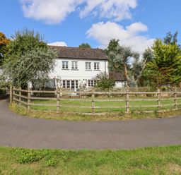 A white two-story house with multiple windows surrounded by trees and a wooden fence at Culver Court Cottage in Venny Tedburn near Crediton