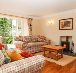 A living room with plaid sofas cushions wooden coffee table and a wood burning stove at Culver Court Cottage Venny Tedburn near Crediton