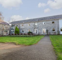 An outdoor courtyard with tables and chairs in front of a two-story stone and white building at The Bevan in Bontnewydd Gwynedd