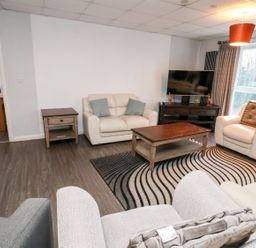 A living room with armchairs sofa coffee table and television at Cadwaladr in Bontnewydd near Caernarfon