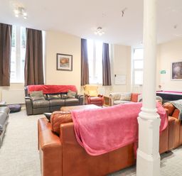 A lounge with sofas, armchairs, a coffee table, a mounted television, and a pool table at The Lombard in Dolgellau