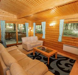 A living room with leather sofas a coffee table a television and blue patterned curtains at Bamboo Retreat in Louth