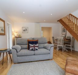 A living room with a sofa and dining area at Mariners Rest in Gorran Haven