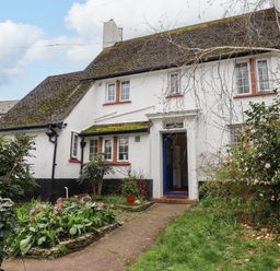 A house exterior with white walls a blue door garden plants and flowers at Greenhedges in Budleigh Salterton