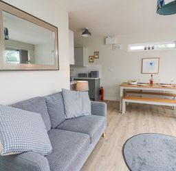 A living room with a sofa and dining table with benches at 36 Coedrath Park in Saundersfoot
