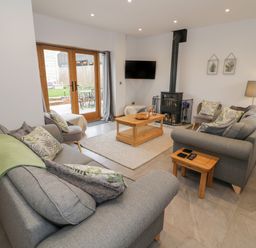 A living room with two grey sofas a wood-burning stove and a wooden coffee table at The Stables in Droitwich Spa