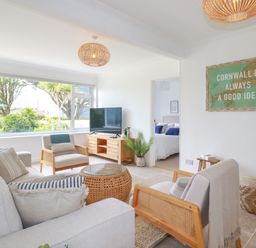 A living room with armchairs a sofa a television and a framed map on the wall at Polwen in Harlyn Bay Padstow