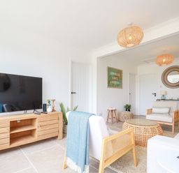 A living room with wooden furniture a television and a sign on the wall at Polwen in Harlyn Bay Padstow