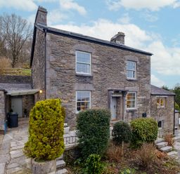 A stone house with four windows a front door and shrubs in front at Sunny Brae in Lindale