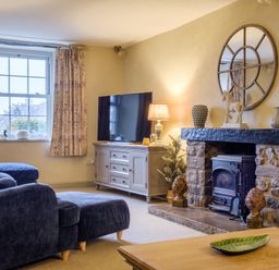 A living room with a stone fireplace a round mirror a television and a blue sofa at Sunny Brae in Lindale