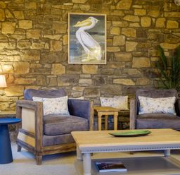 A sitting area with two armchairs a coffee table a side table a lamp a framed pelican picture and a potted plant at Sunny Brae in Lindale