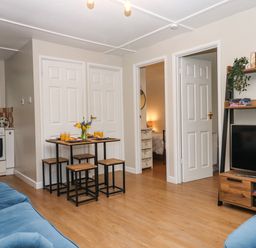 A living room with a wooden dining table set and blue sofas at 2 The Glade in Kilkhampton