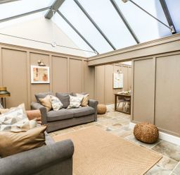 A living room with two grey sofas and a woven rug under a glass ceiling at The Apple Loft at Jordan House in Preston
