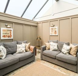 A seating area with two gray sofas with pillows and a small round table with a lamp between them at The Apple Loft at Jordan House in Preston