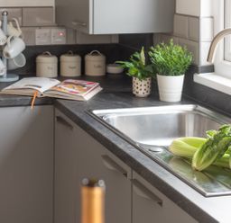 A kitchen sink with celery and lettuce on the counter and jars labeled tea sugar coffee Wheal Amelia Lodge Wendron near Helston