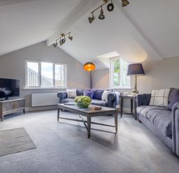 A living room with two sofas a coffee table a television and a wood stove at Gate House in Killington near Sedbergh