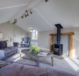 A living room with sofas a coffee table a wood burning stove and an armchair at Gate House in Killington near Sedbergh