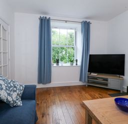 A living room with a sofa, television, and window at Ty Capel Bethania in Nant Gwynant