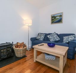 A living room with a sofa, coffee table, and wood stove at Ty Capel Bethania Nant Gwynant