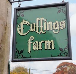 A green sign with old style font saying Cullings farm outdoors