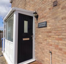 An entrance with a door and sign at Lavender Cottage Beadnell