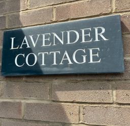 A sign reading Lavender Cottage on a brick wall at Lavender Cottage in Beadnell