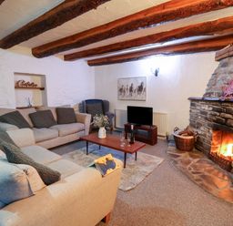 A living room with two sofas armchair a coffee table and a stone fireplace with a fire at Ty Ceffylau in Llanllwni near Llanybydder