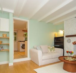 A living room with a beige sofa and wooden coffee table in front of a fireplace at 15 The Moors in Lostwithiel