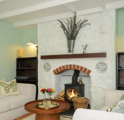 A living room with a fireplace two sofas a round wooden table and wooden bookshelves at 15 The Moors in Lostwithiel