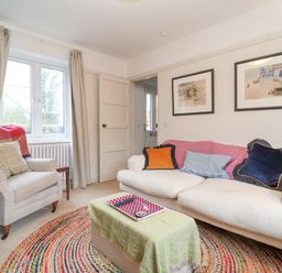 A living room with a white sofa and armchair a window with curtains and framed pictures on the wall at 3 Chantry Cottages Campsea Ashe near Woodbridge