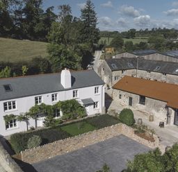 An outdoor view of a house and farm buildings at Lower Well Farm House in Totnes