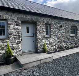 An outdoor area with a stone wall and steps at Beudy Tanrallt in Llanfachraeth