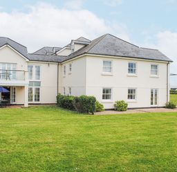 A building with multiple windows and balconies facing a large green lawn at 5 Thurlestone Beach in Thurlestone