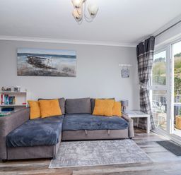 A living room with a sofa and shelves at Shells Cottage in Looe