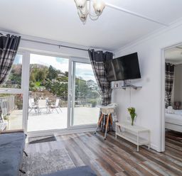 A living room with a television and a sofa at Shells Cottage in Looe