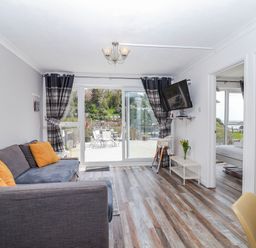 A living room with a sofa and television at Shells Cottage in Looe