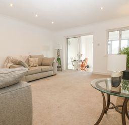 A living room with beige sofas a floor lamp a glass side table with a lamp and a stone fireplace at Riverview Apartment in Cemaes Bay