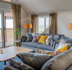 A living room with two sofas with colorful cushions a wooden coffee table and floor lamps at Villa 1 Mullion
