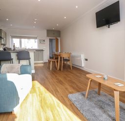 A living room with a blue armchair wooden coffee table and wall mounted TV at 2 South Street in Fletchertown near Aspatria