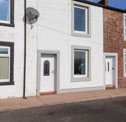 Exterior view of terraced houses with white and red brick facades and white doors at 2 South Street Fletchertown near Aspatria