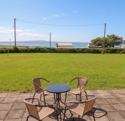 A garden with a table and chairs overlooking the sea at The Boathouse, Carrigaholt, County Clare