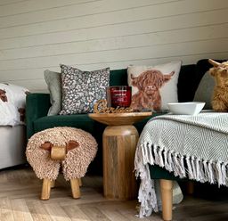 A living room with a couch, pillows, candle, and a wooden table at Willow in Llangurig near Llanidloes