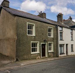 A row of attached houses with windows and chimneys along a street at Eden Vale in Broughton-In-Furness