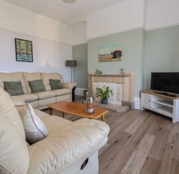A living room with beige sofas a wooden coffee table a fireplace and a television at 46 The Promenade in Withernsea