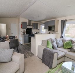 A living room with sofas and cushions next to a kitchen and dining table with chairs at 43 The Deri in Llanarth