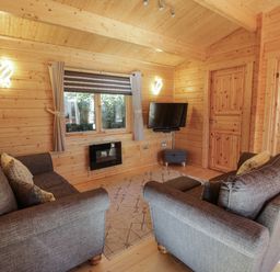 A living room with two gray sofas a wall mounted TV and a window at Little Lodge in Balminnoch near Glenluce